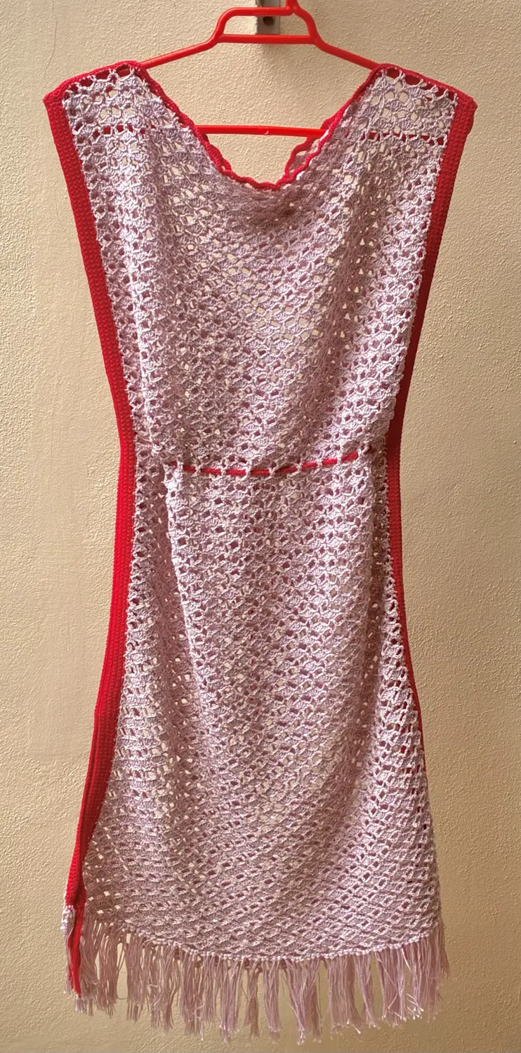 Front view of the finished crochet dress hanging from a red hanger